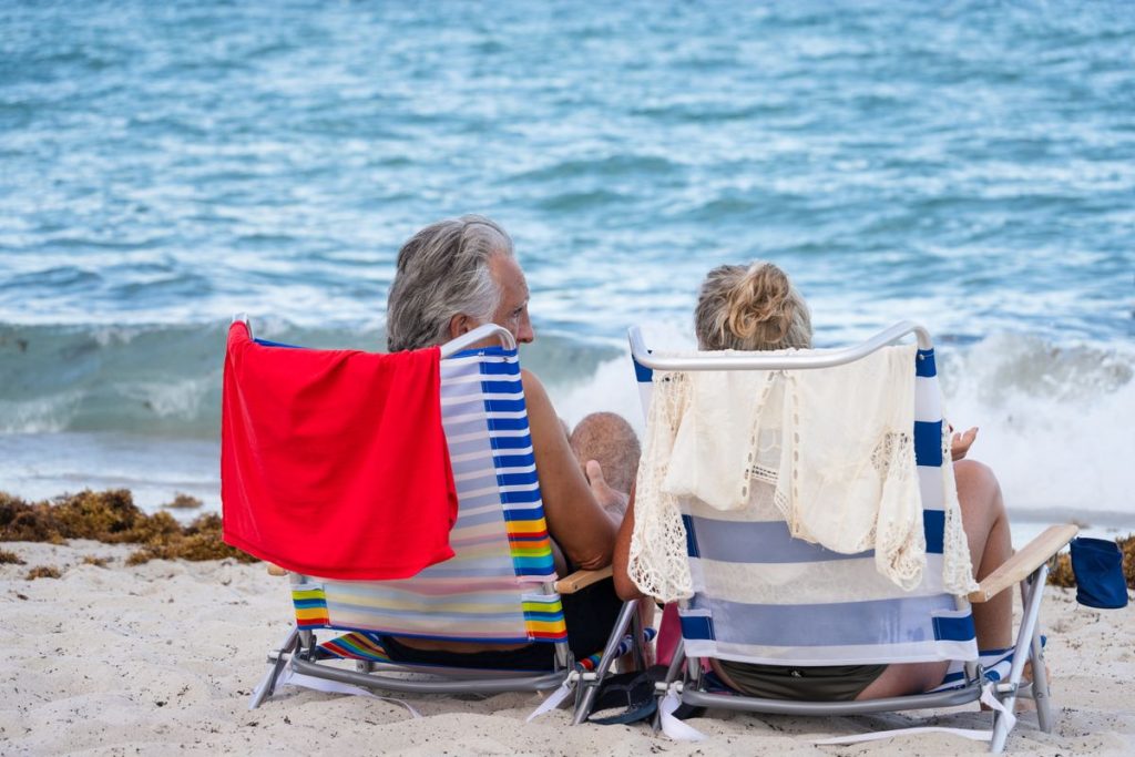 Entspanntes älteres Ehepaar blickt gemeinsam aufs Meer – Sinnbild für eine gut geplante Altersvorsorge