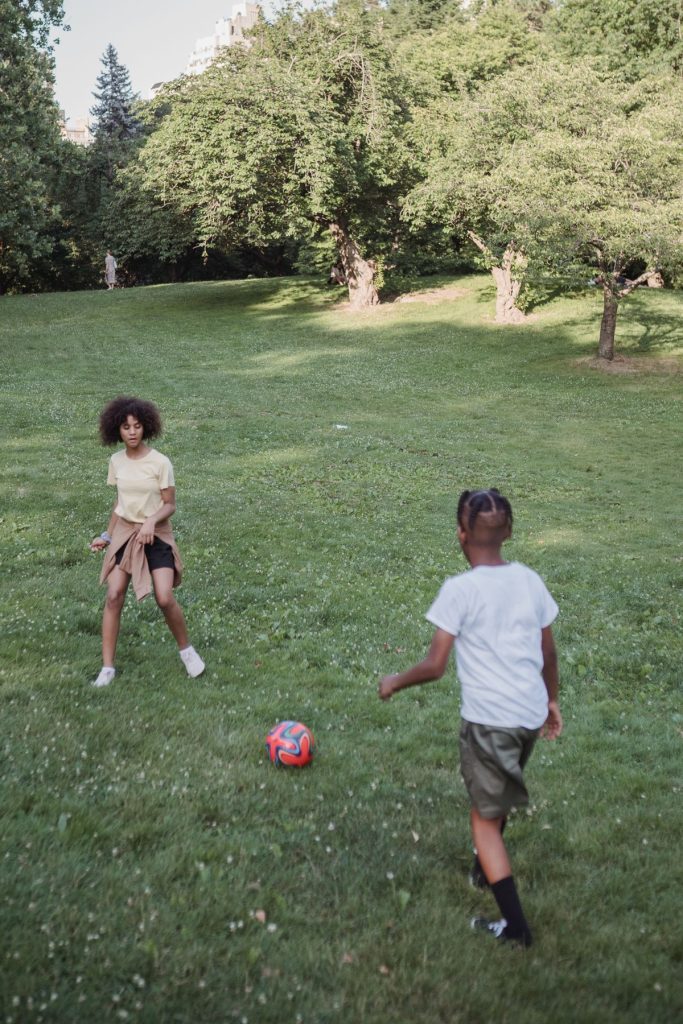 Zwei Kinder spielen Fußball im Park – typische Freizeitunfälle, die die gesetzliche Unfallversicherung nicht abdeckt